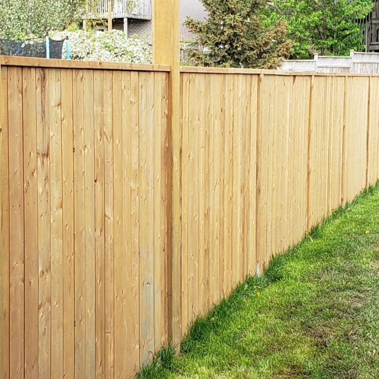 Wood privacy fence lining a green backyard lawn in Conroe