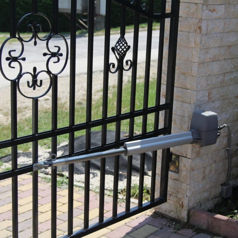 Gate hinge and opener arm hardware mounted on a metal driveway gate