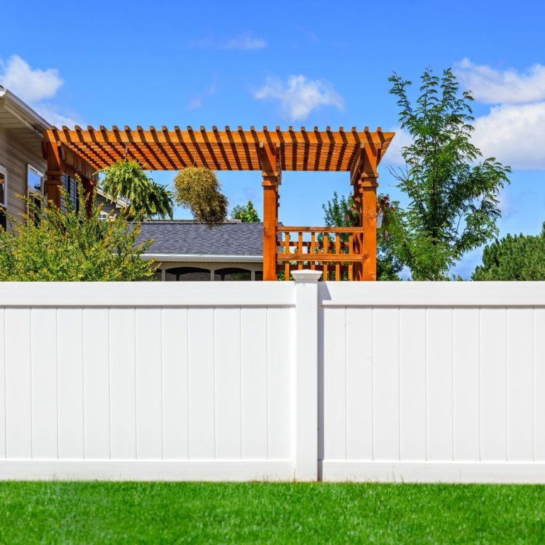 White vinyl privacy fence with a backyard pergola behind it in Conroe Texas